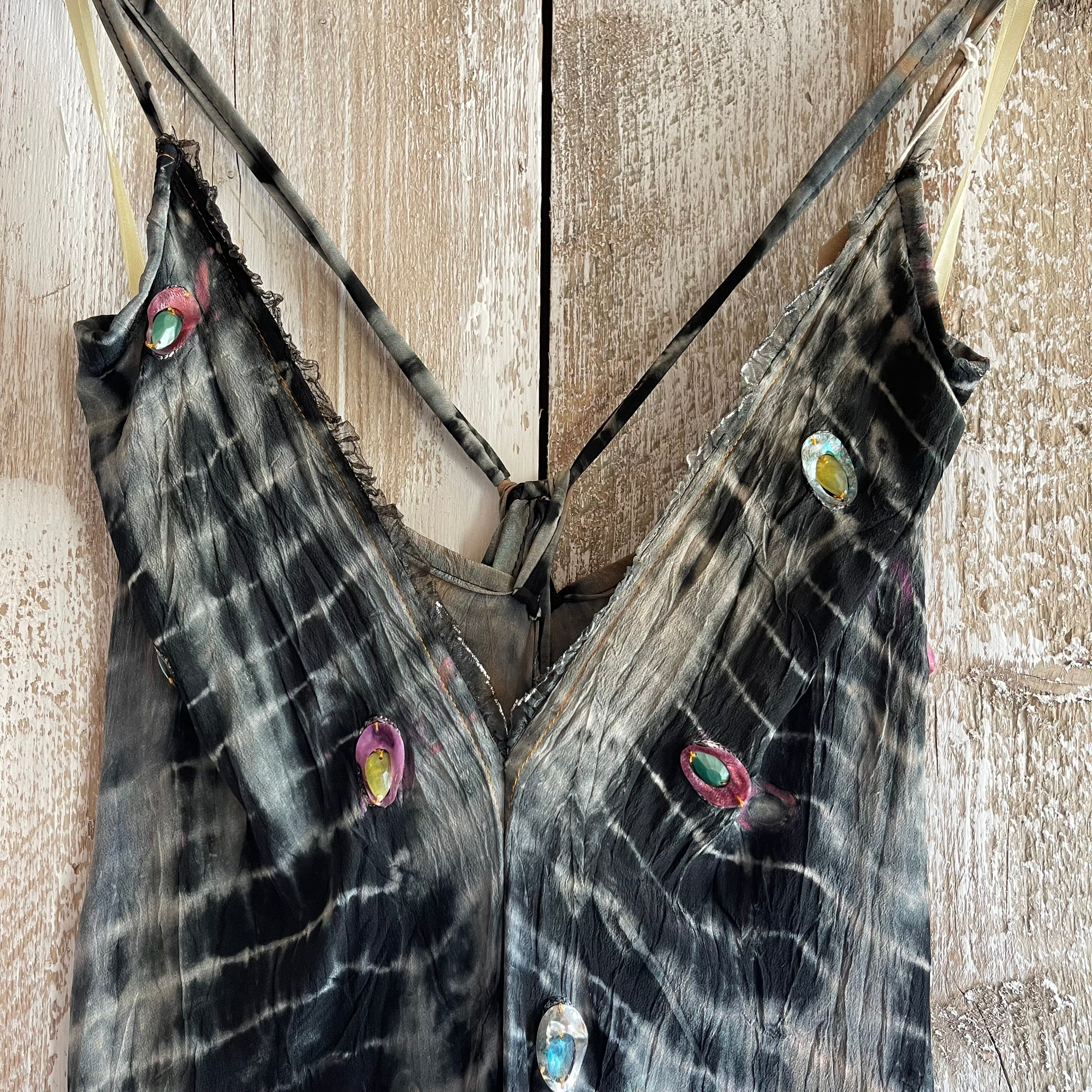 Tie-dye dress with embellishments hanging on a wooden surface