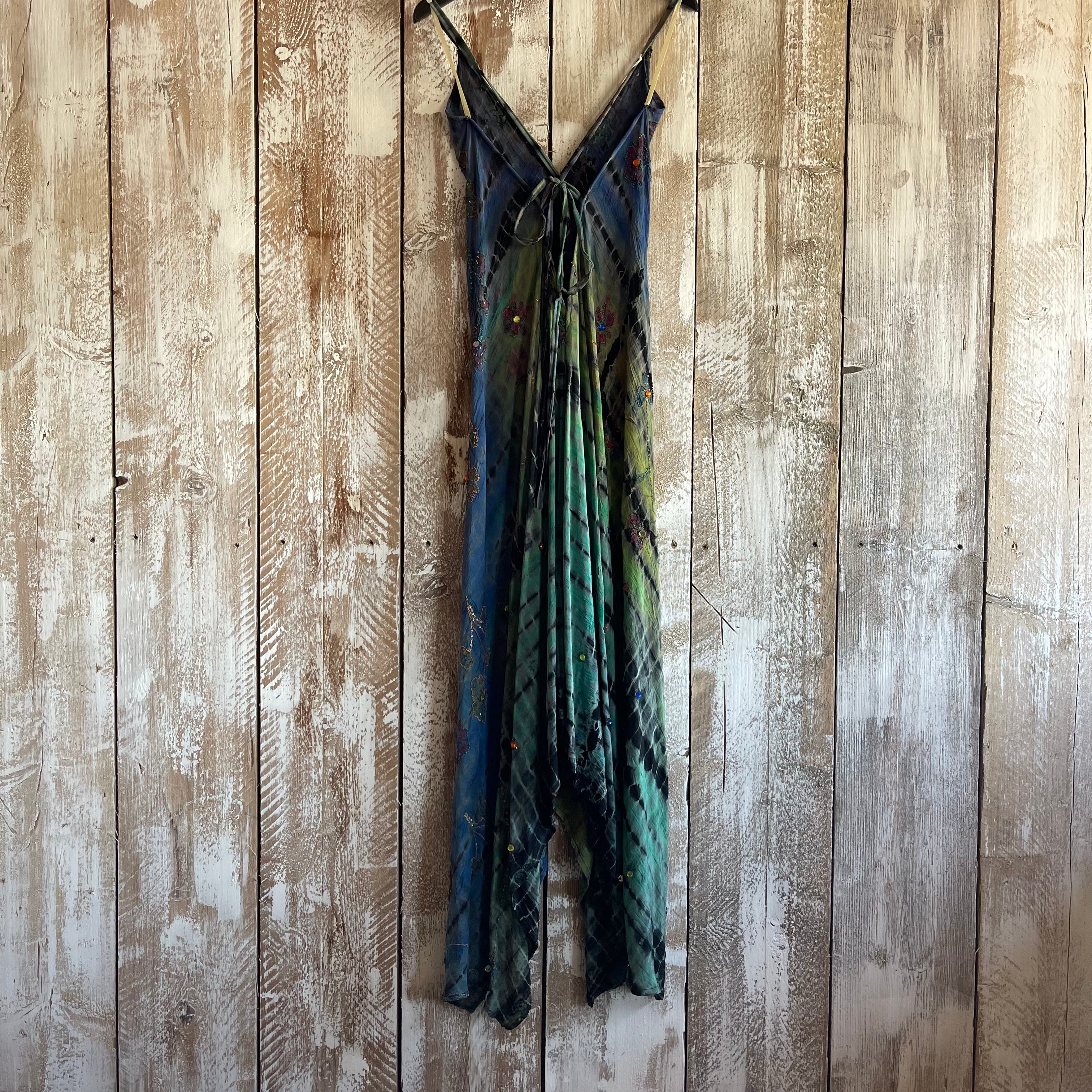Green and blue patterned dress hanging on a wooden wall