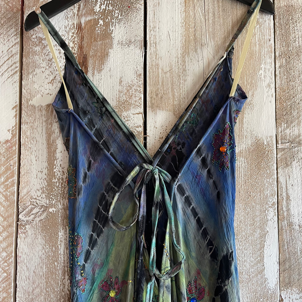 Blue floral dress with thin straps hanging on a wooden surface