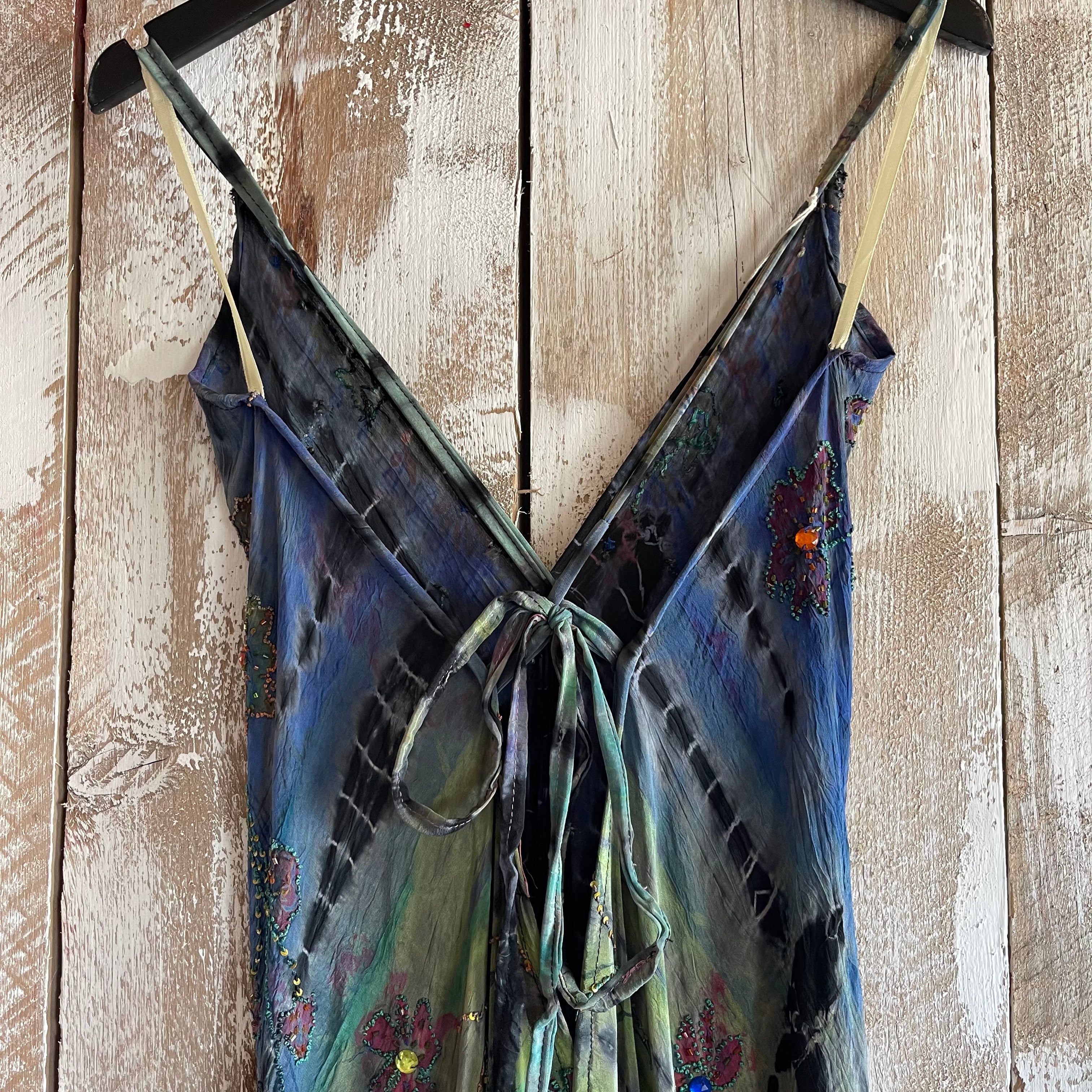 Blue floral dress with thin straps hanging on a wooden surface