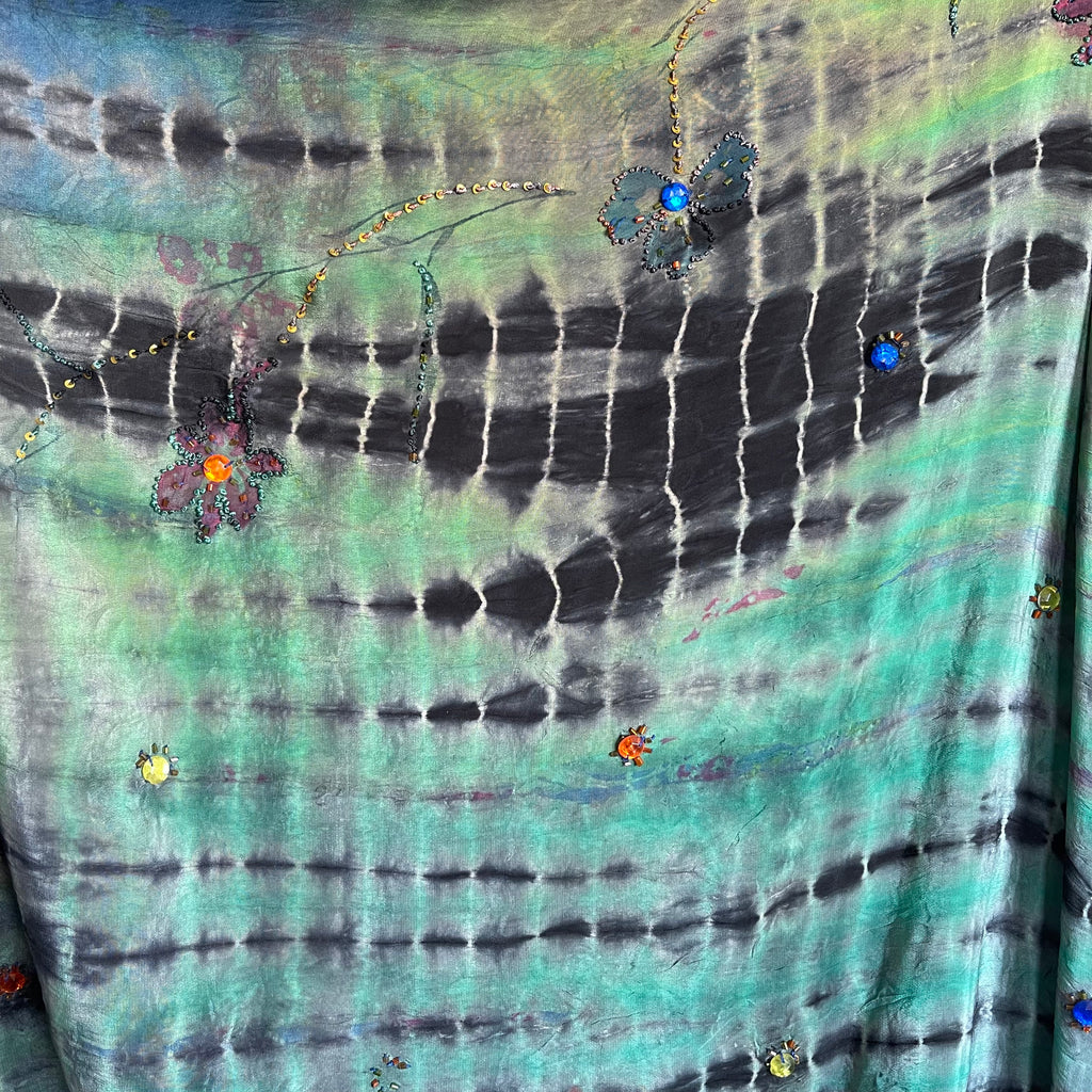 Tie-dye fabric with abstract patterns and small colorful embellishments