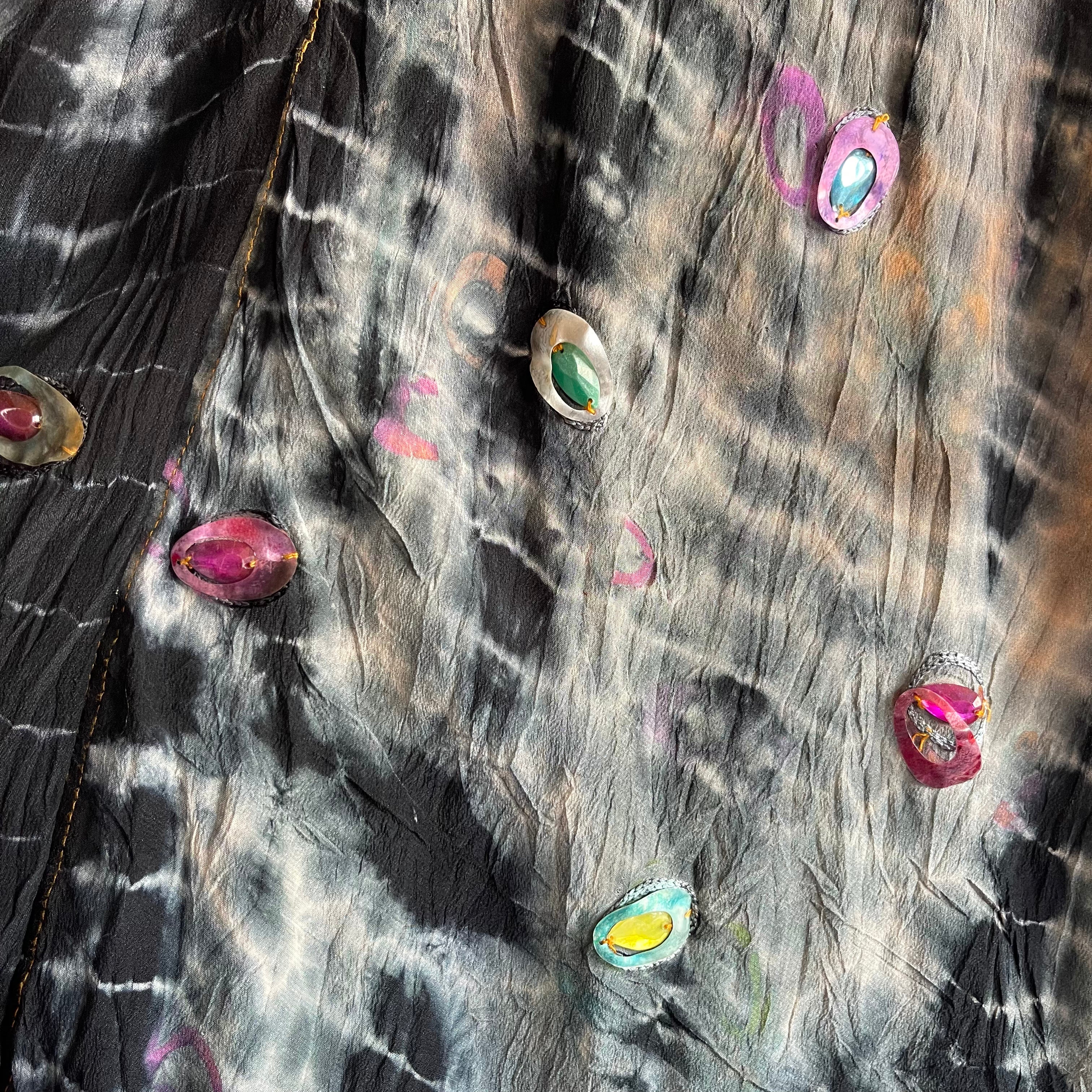 Colorful gemstone earrings on a textured surface