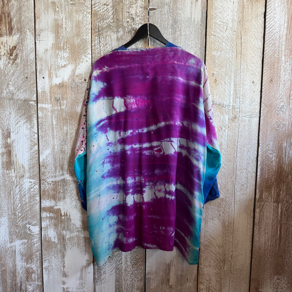 Tie-dye shirt on a hanger against a wooden wall