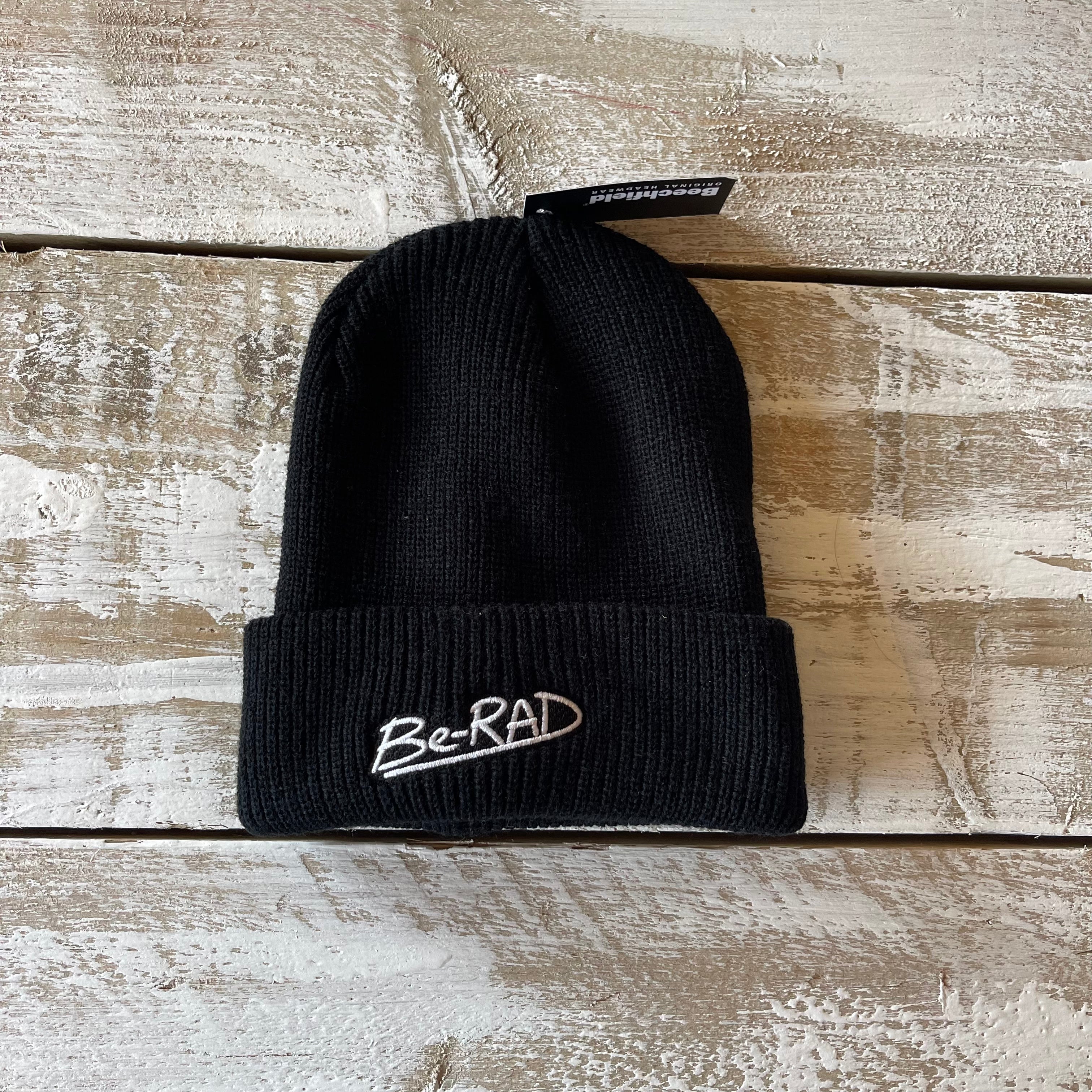 Black beanie with 'Be-RAD' logo on a wooden surface