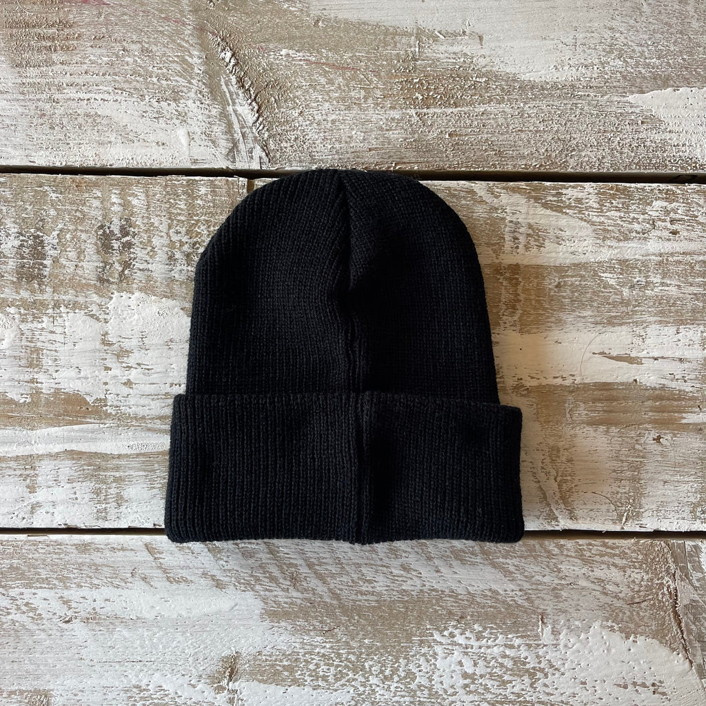 Black knit beanie on a wooden surface