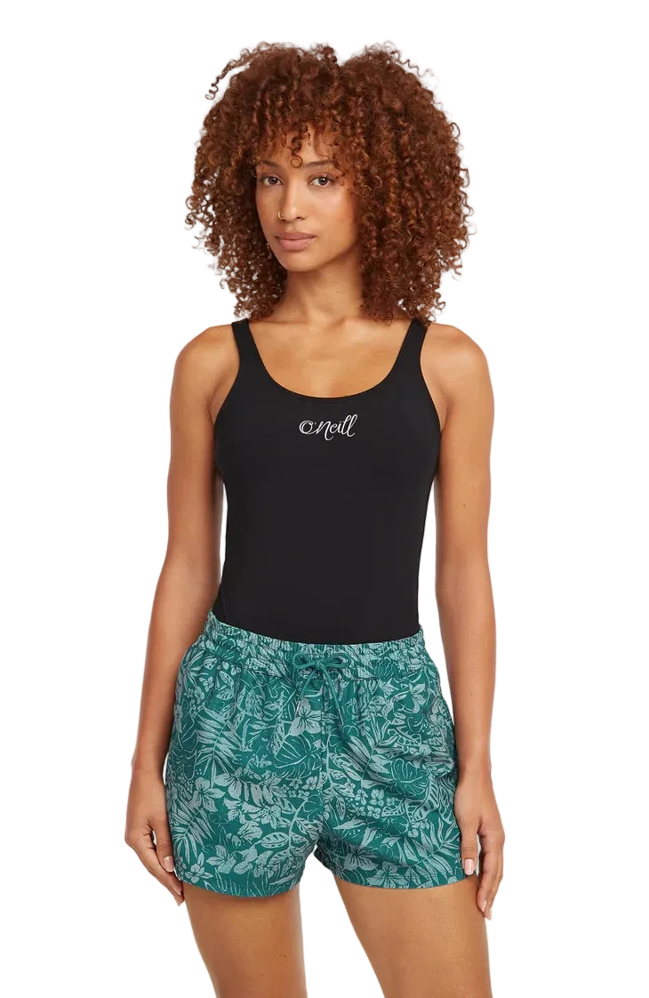 Woman wearing a black tank top and green patterned shorts on a white background