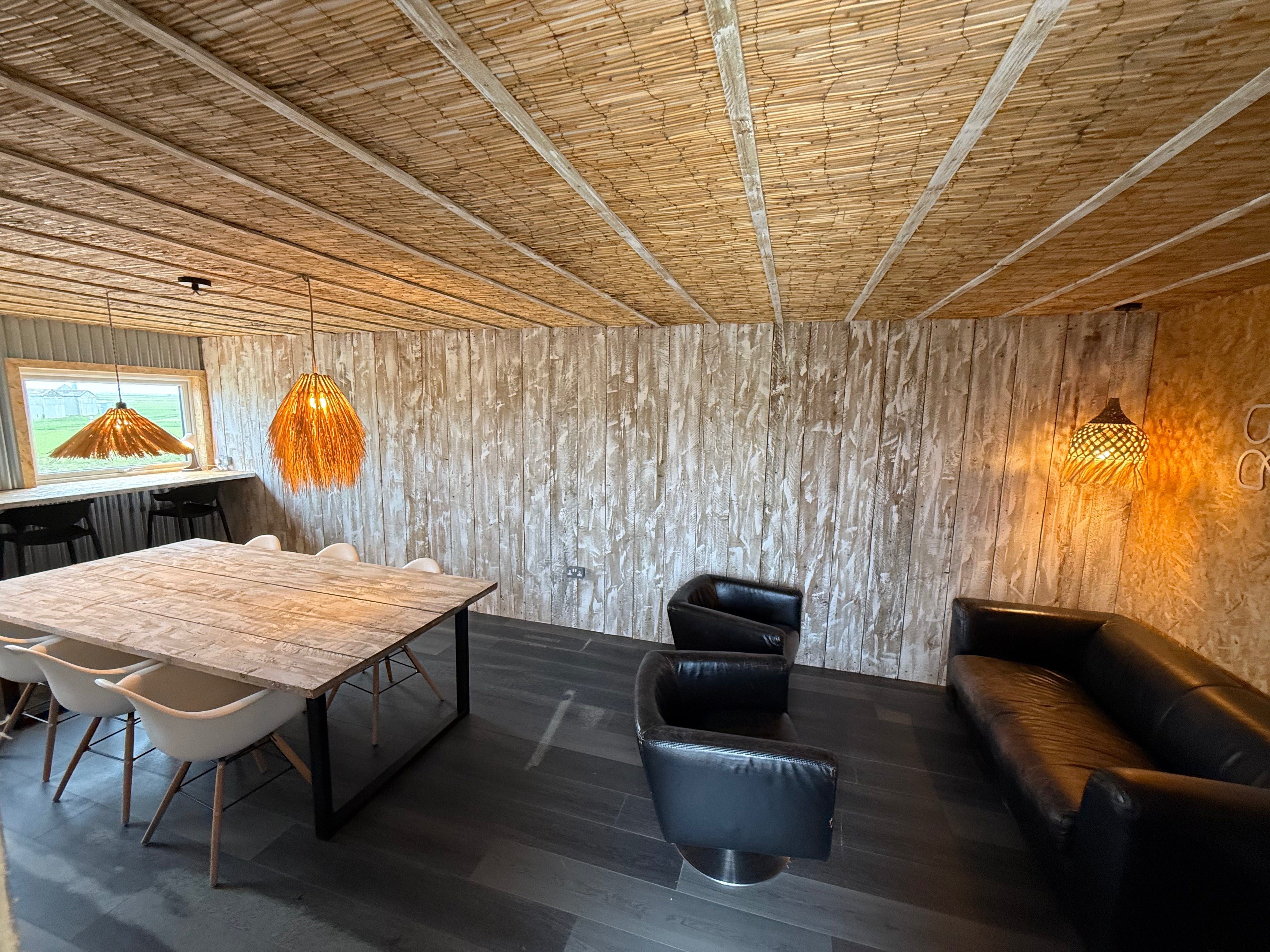 Modern interior with wooden ceiling, table, chairs, and a sofa.